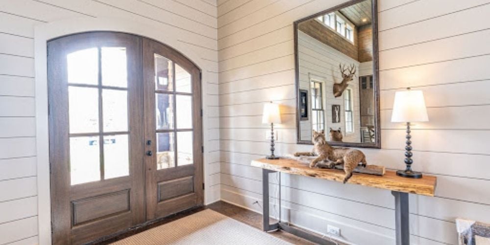 Beautiful dark wood front door with white wood panel walls. 