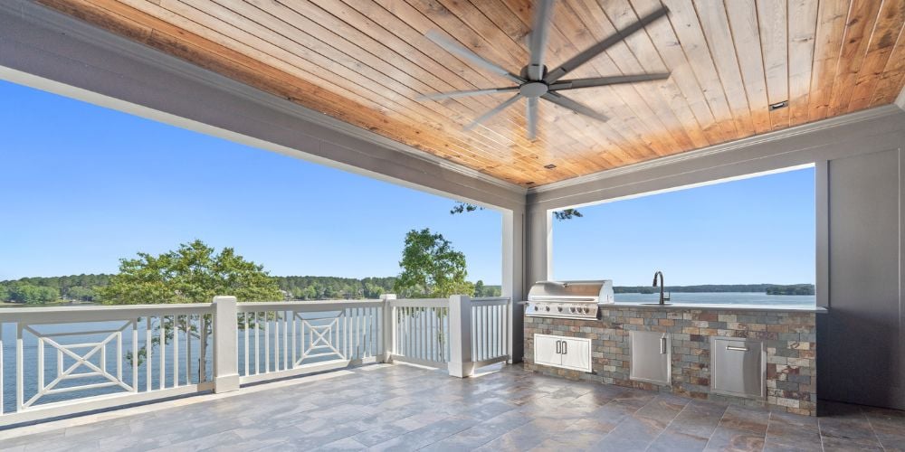 Waterfront Outdoor Living Space on Lake Oconee, GA with Outdoor Kitchen Area and Large Ceiling Fan by PAXISgroup Custom Home Builders in GA