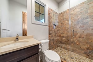 Single Vanity Bathroom with Warm Stone Walk-in Shower | PAXISgroup