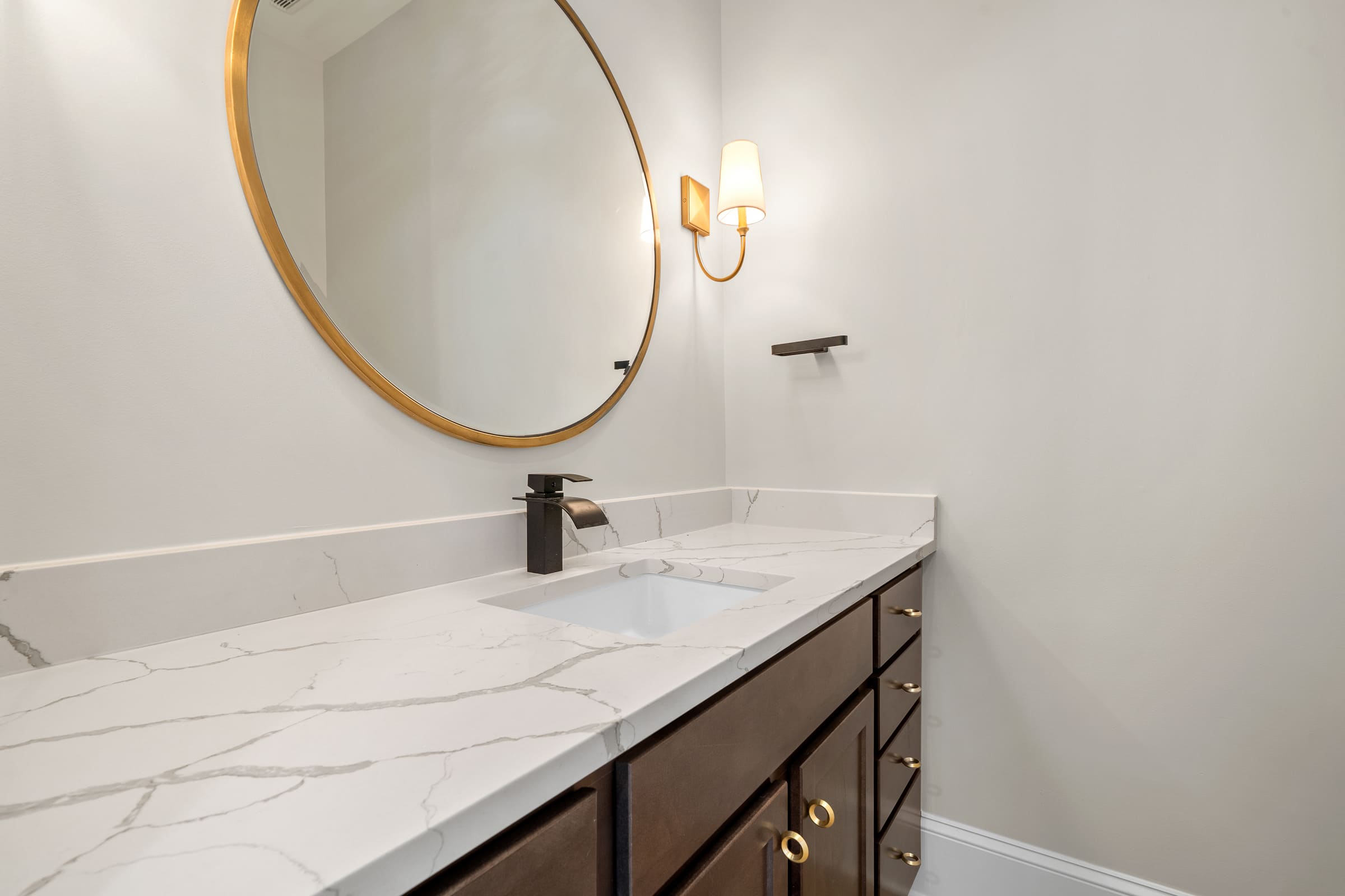 Bathroom with White Marble Coutnertop and Dark Wood Cabinets with Gold Accents |PAXISgroup