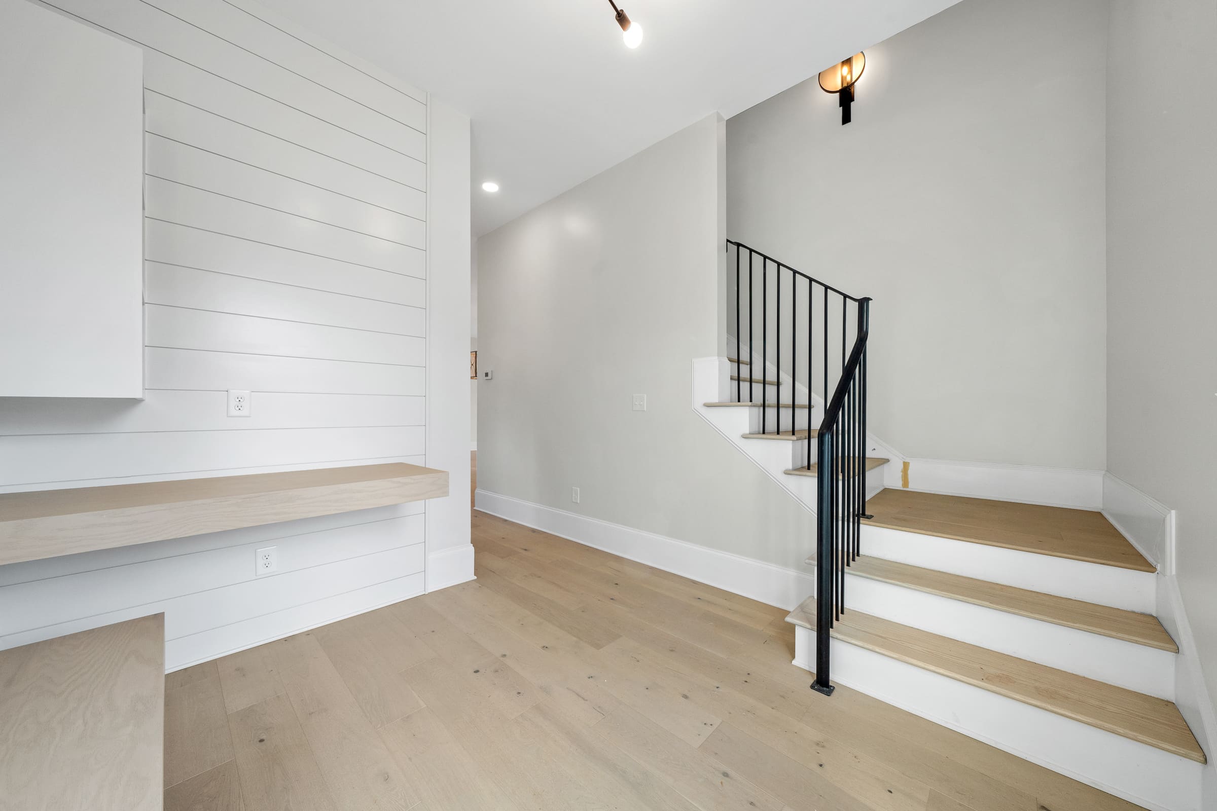 Stunning White and Open Entrance with Light Wood Flooring and Black Staircase Banaster |PAXISgroup