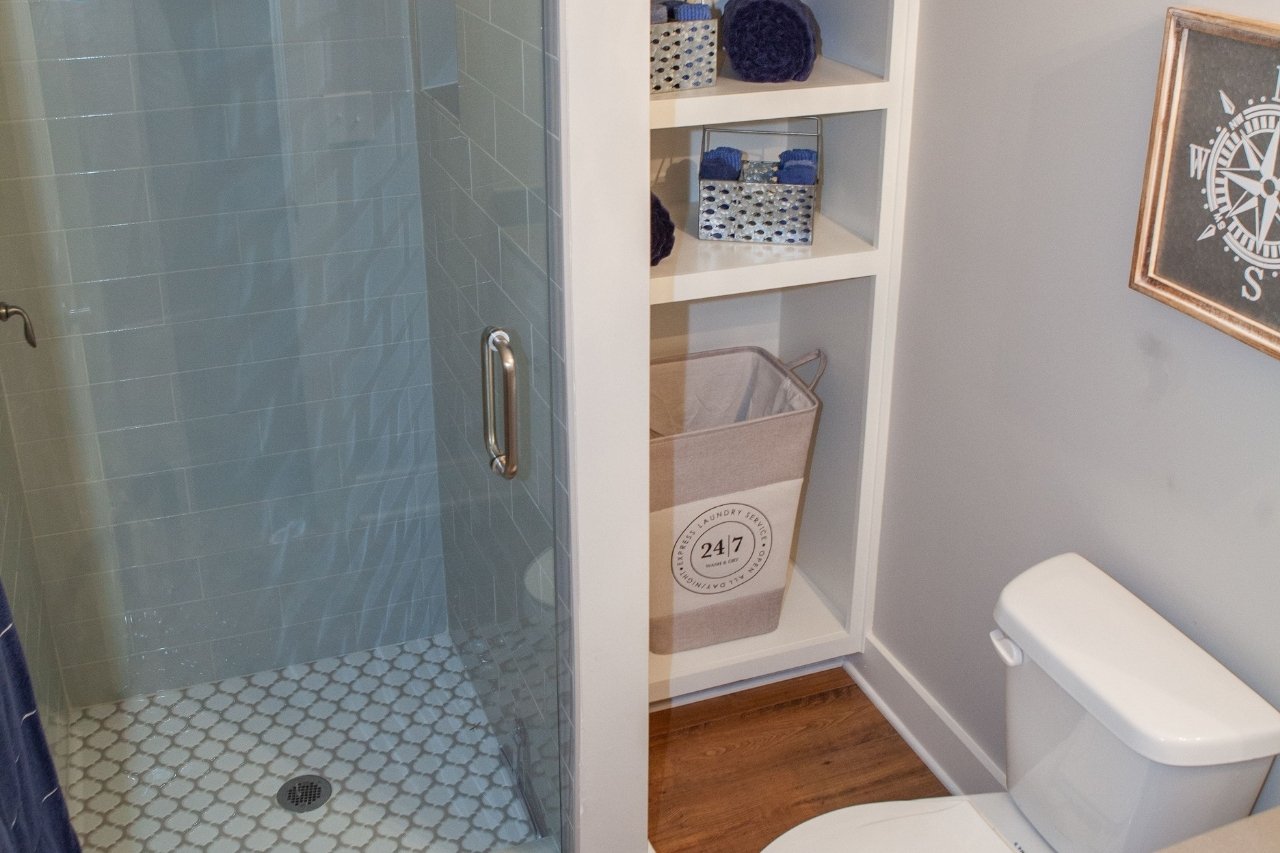 Downstairs Guest Bathroom with Glass Door Shower and Built-In Storage Shelving | PAXISgroup Custom Home Builders in GA