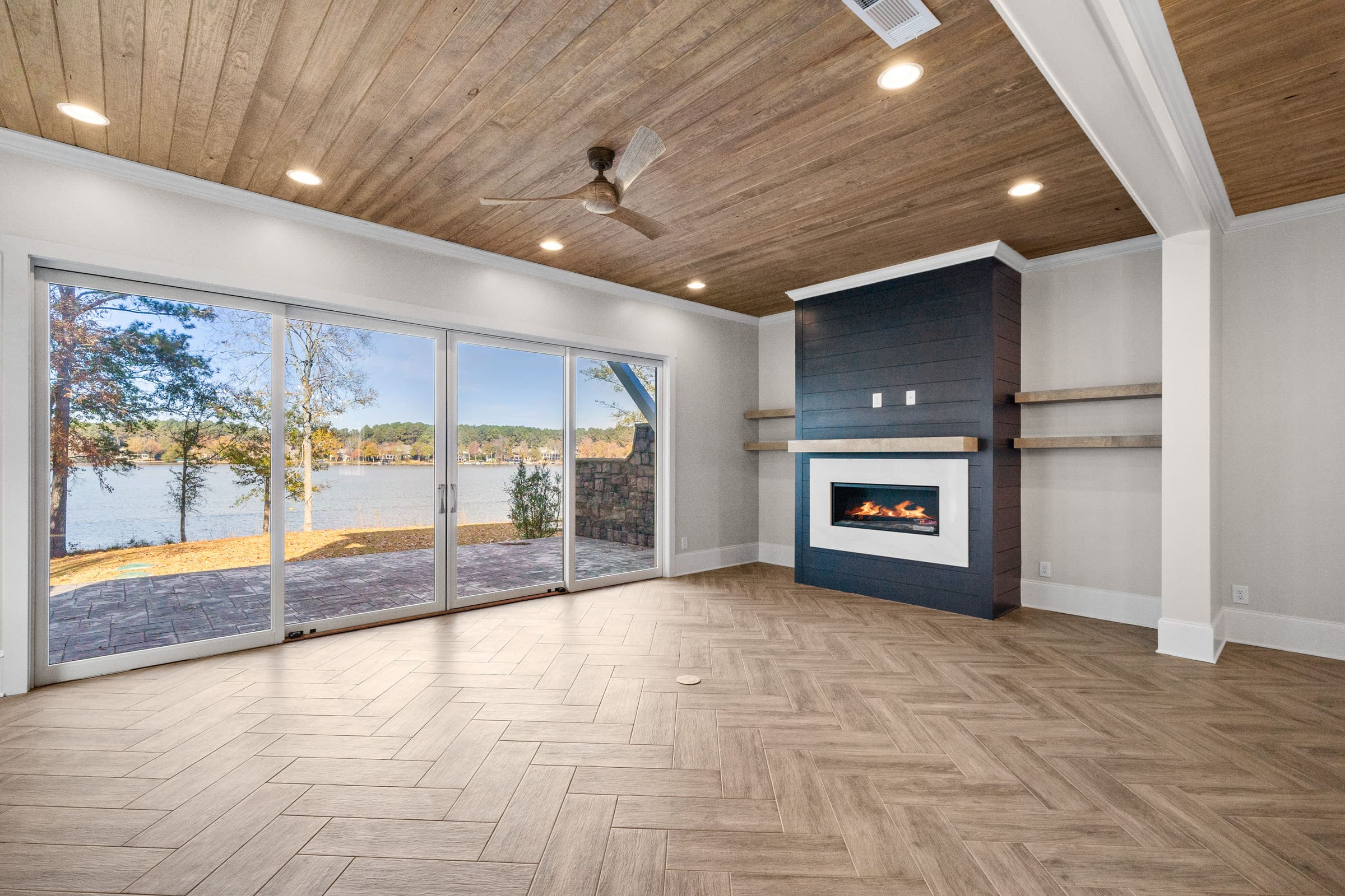 Dark Hardwood Fireplace with White Features with View of Full Glass Wall Leading to Backyard 