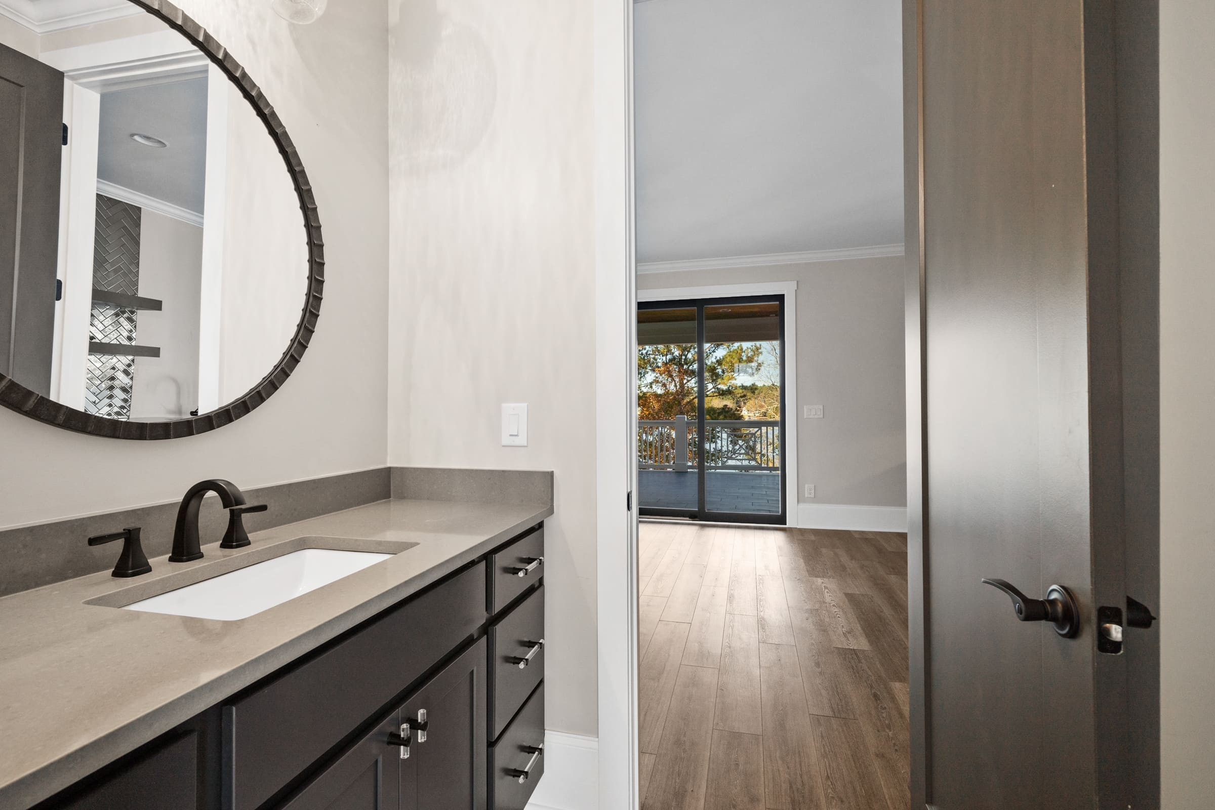 Single Sink Faucet with Dark Wood Cabinetry and Circle Mirror 