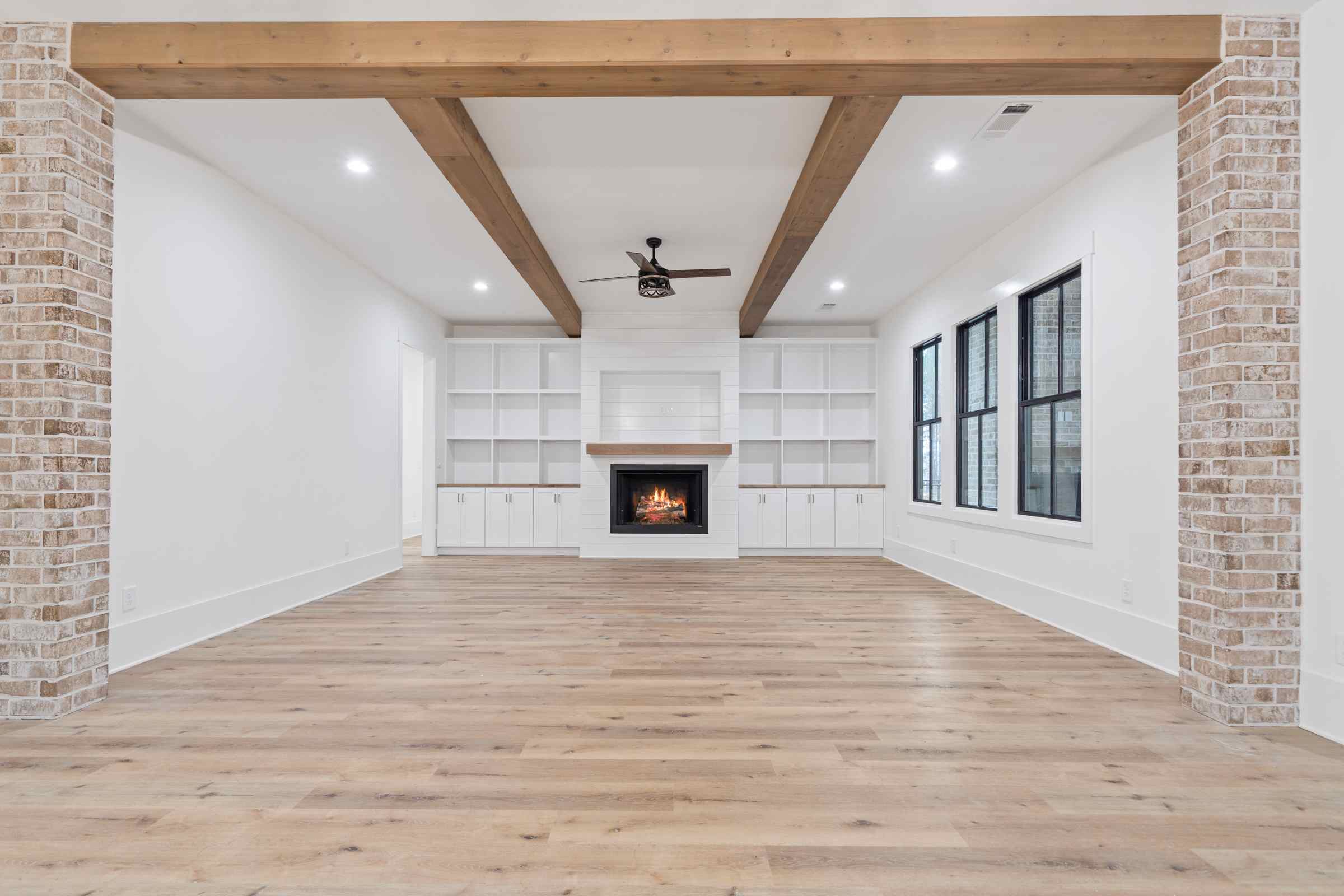 16 Paxis Indian Trail living area, built-in shelving, fireplace, exposed brick, wooden beams | Paxisgroup