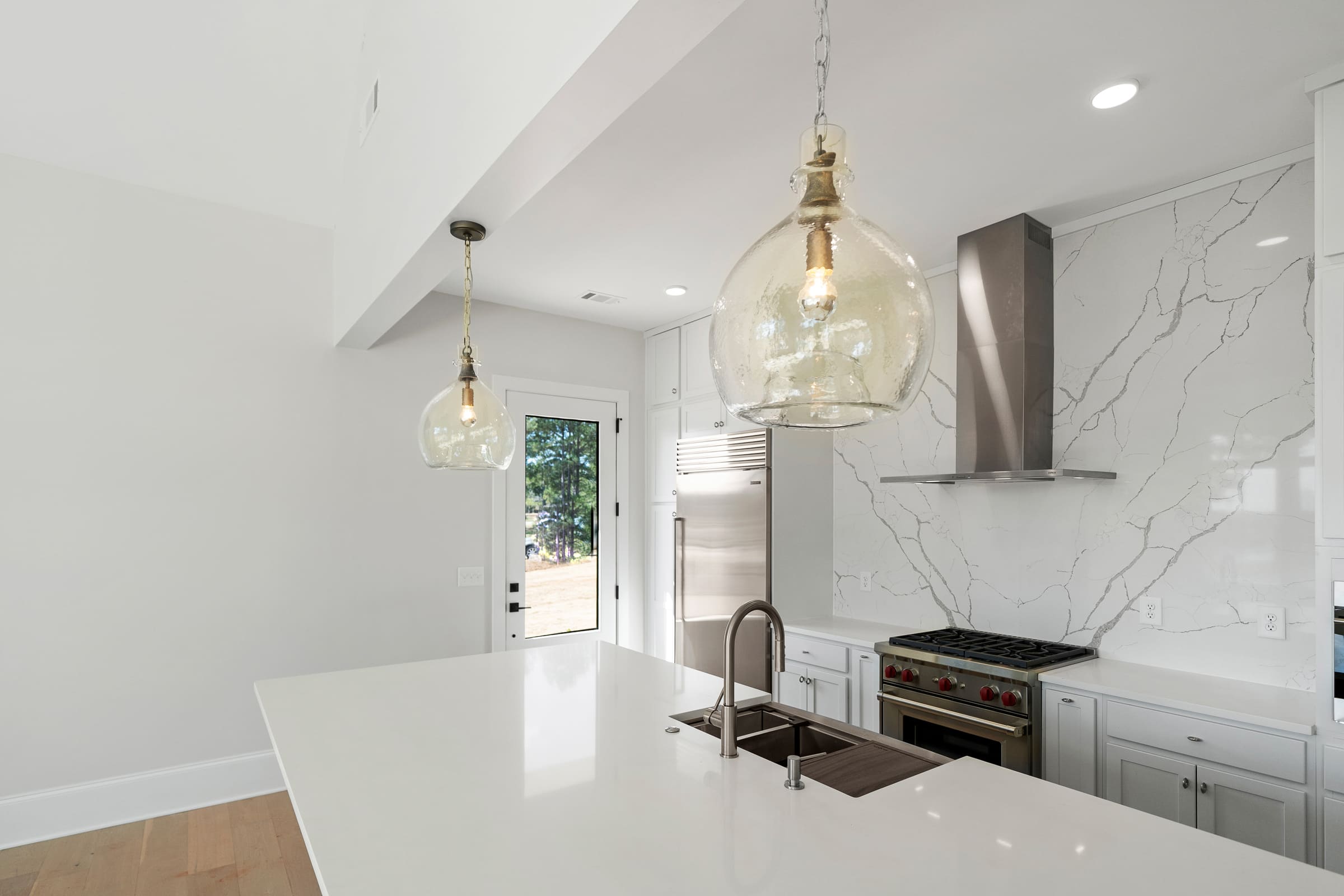 Beautiful Open and White Kitchen with Stainless Steel Cooking Hood and White Marble Wall |PAXISgroup