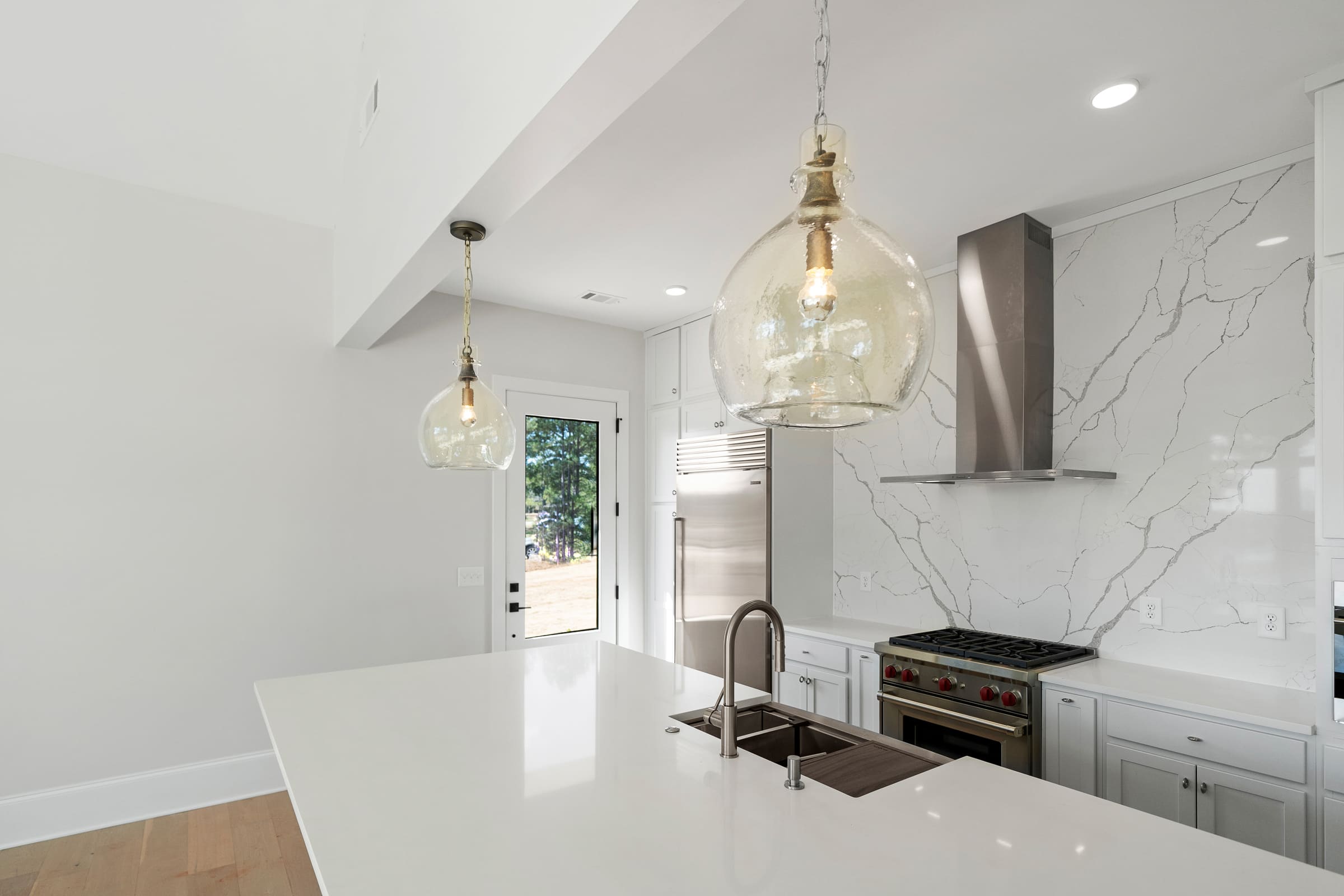 Beautiful Open and White Kitchen with Stainless Steel Cooking Hood and White Marble Wall |PAXISgroup Beautiful Open and White Kitchen with Stainless Steel Cooking Hood and White Marble Wall |PAXISgroup