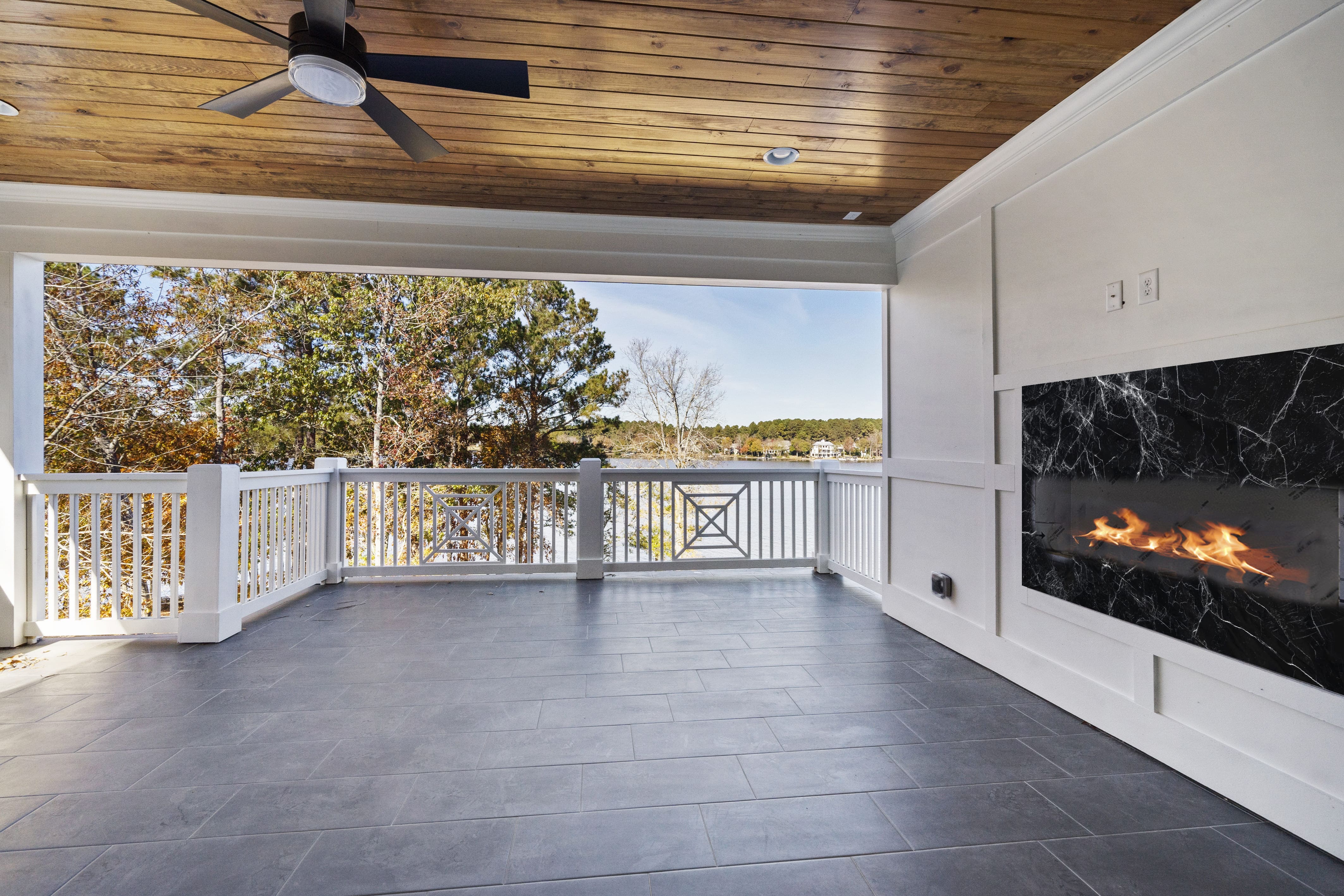 Stone Floored Back Porch with White Fence and White Wall Equipped with a Built-In Black Marble Fireplace