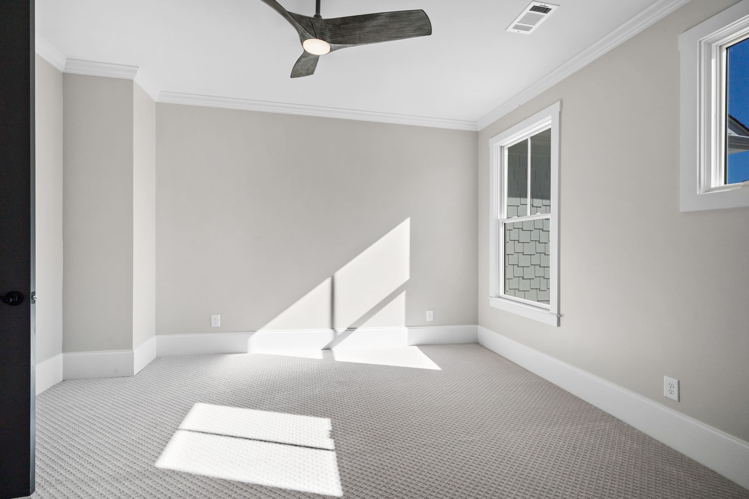 Carpeted Bedroom or Office with Two Windows and Dark Wood Ceiling Fan 